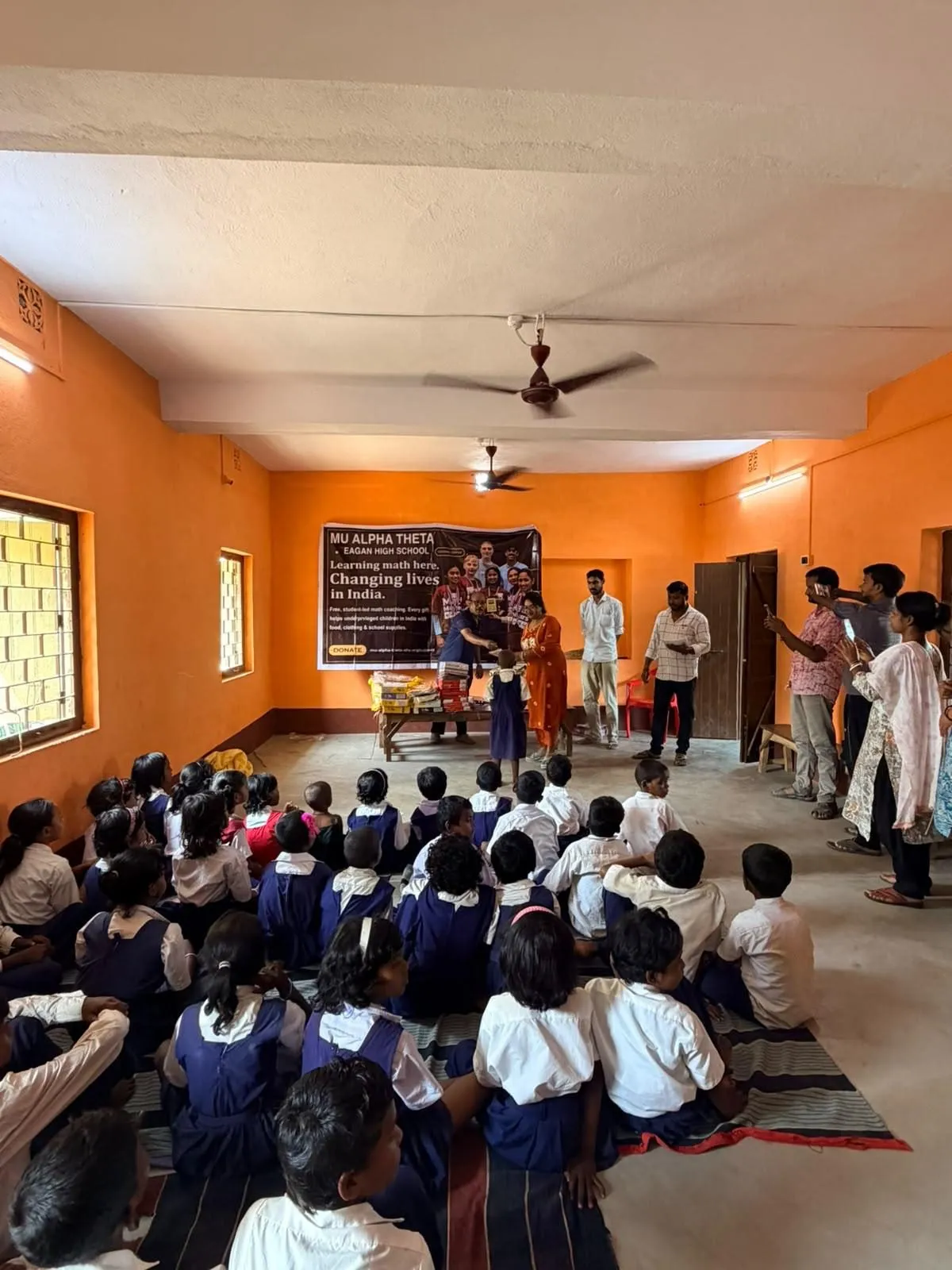 Students sit on the floor of the school hall as the distribution begins