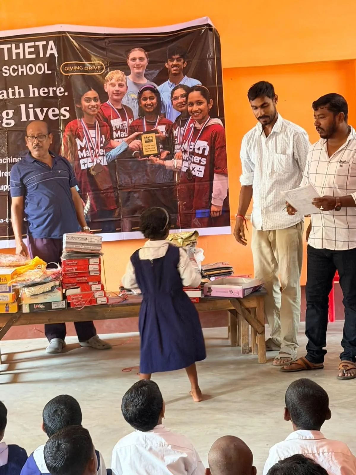 A student receives her new supplies from a table of books and clothing