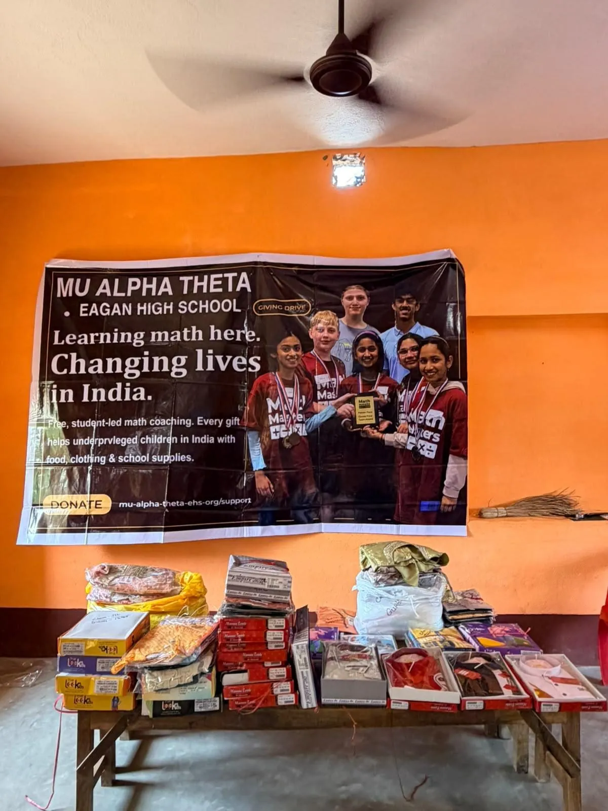 Tables stacked with books, clothing, and school supplies beneath the Mu Alpha Theta banner