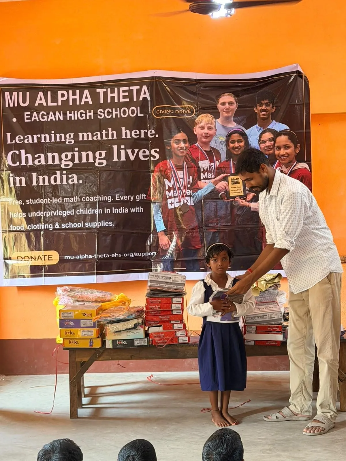 A volunteer hands a student her new supplies