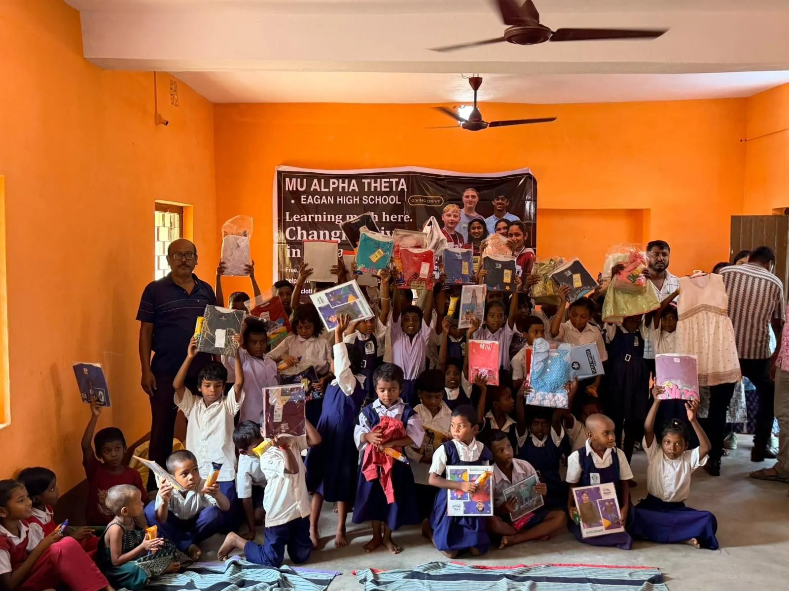 Students and volunteers gather around the banner with their new supplies