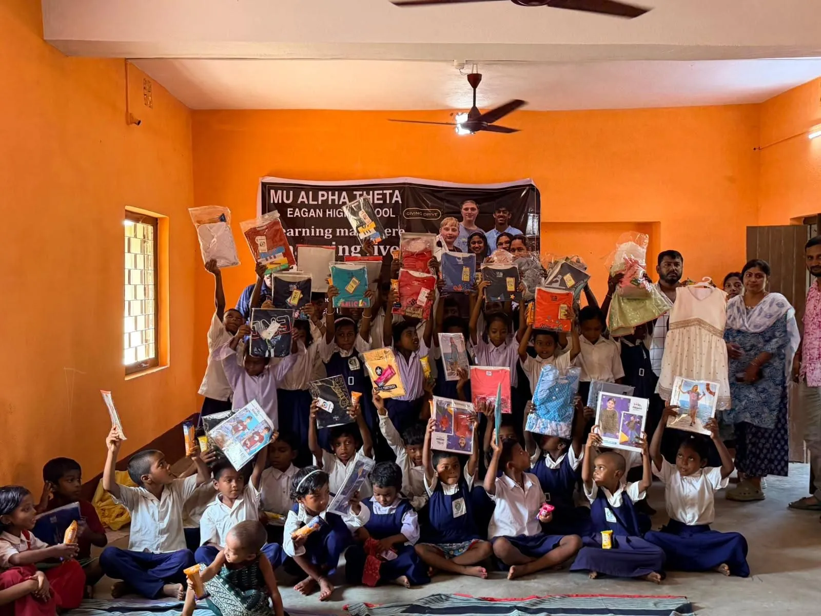 A seated group of students proudly holds up their new books