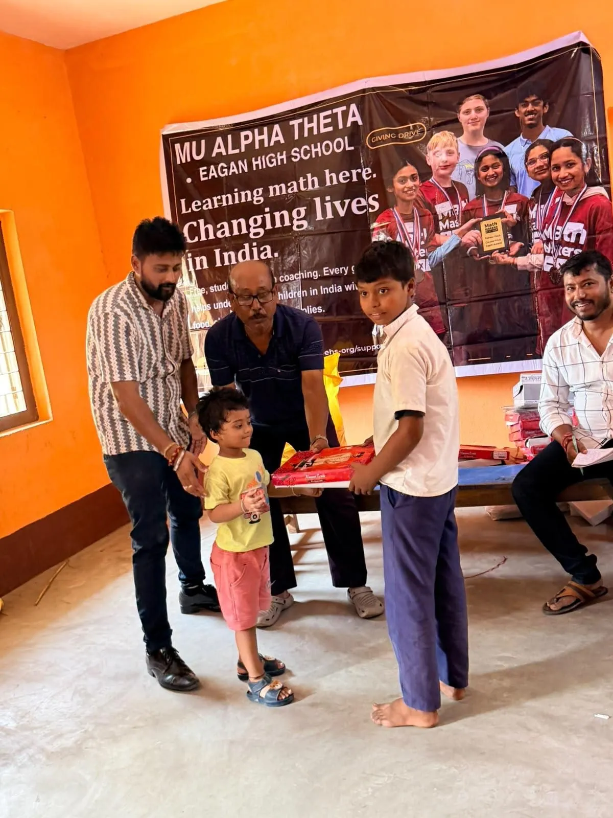 A volunteer hands a young boy a gift