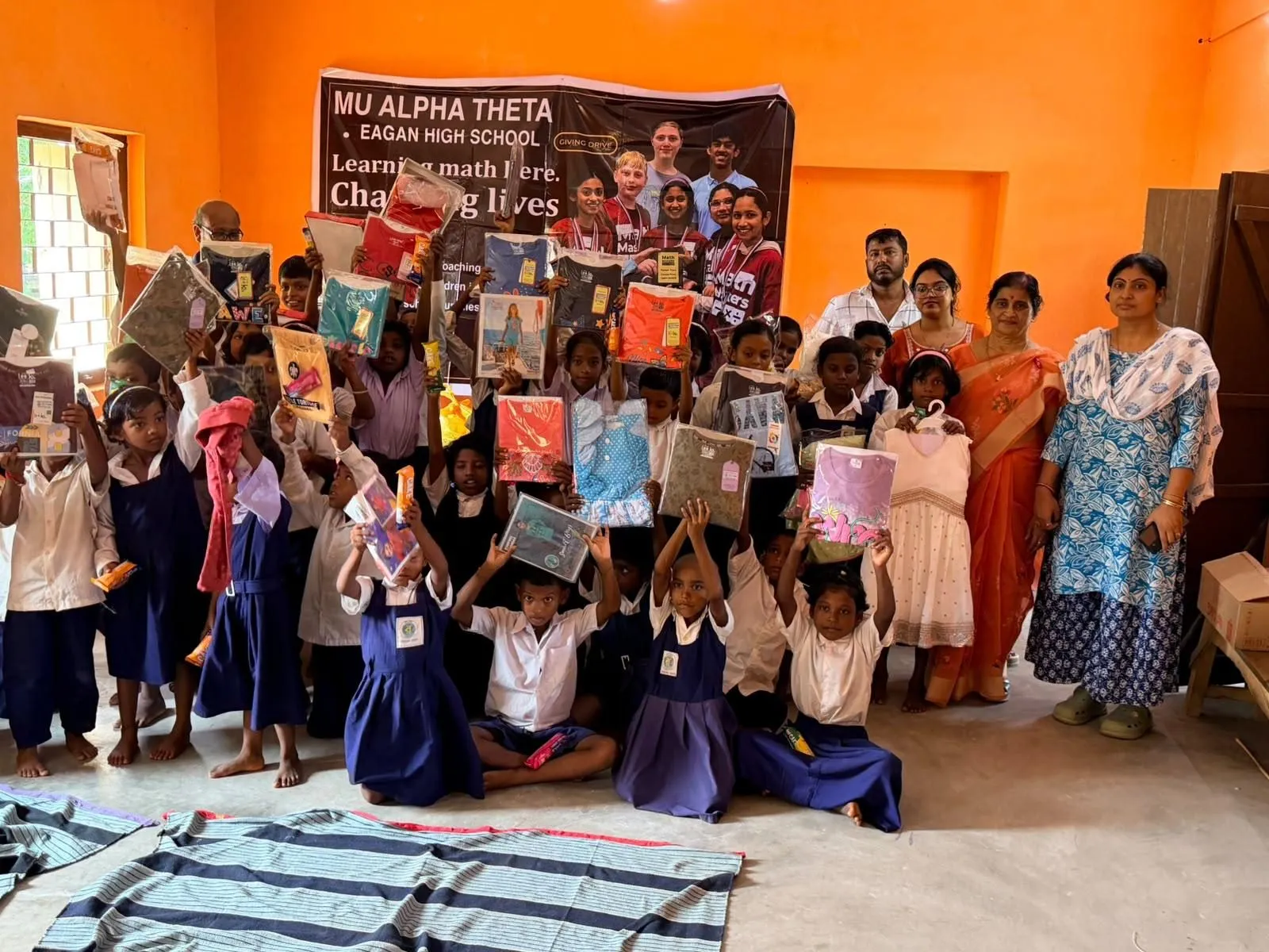 Students lift their new books and supplies high with teachers and volunteers
