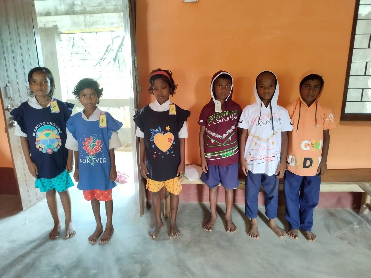 Children stand proudly in their new clothes